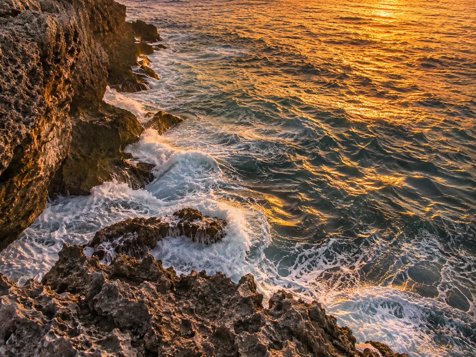 Limestone sea cliffs at sunset with orange light over the water