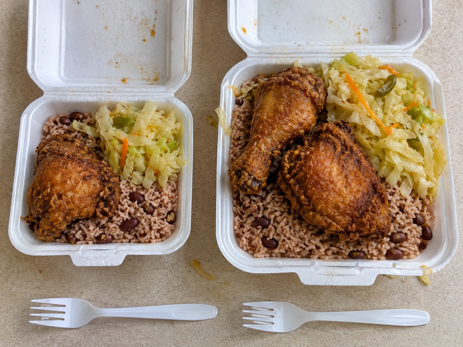 Two foam takeaway boxes side by side, one smaller and one larger, with the lids open