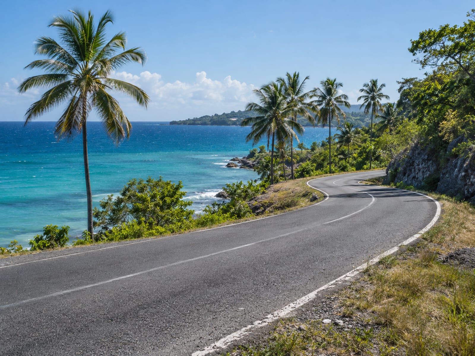 A curving coastal road beside the sea on a clear morning
