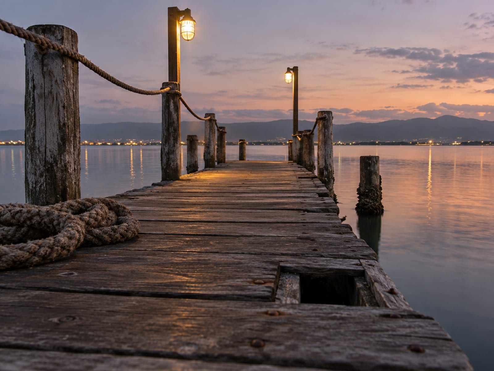 A wooden pier stretching over calm harbour water at dusk