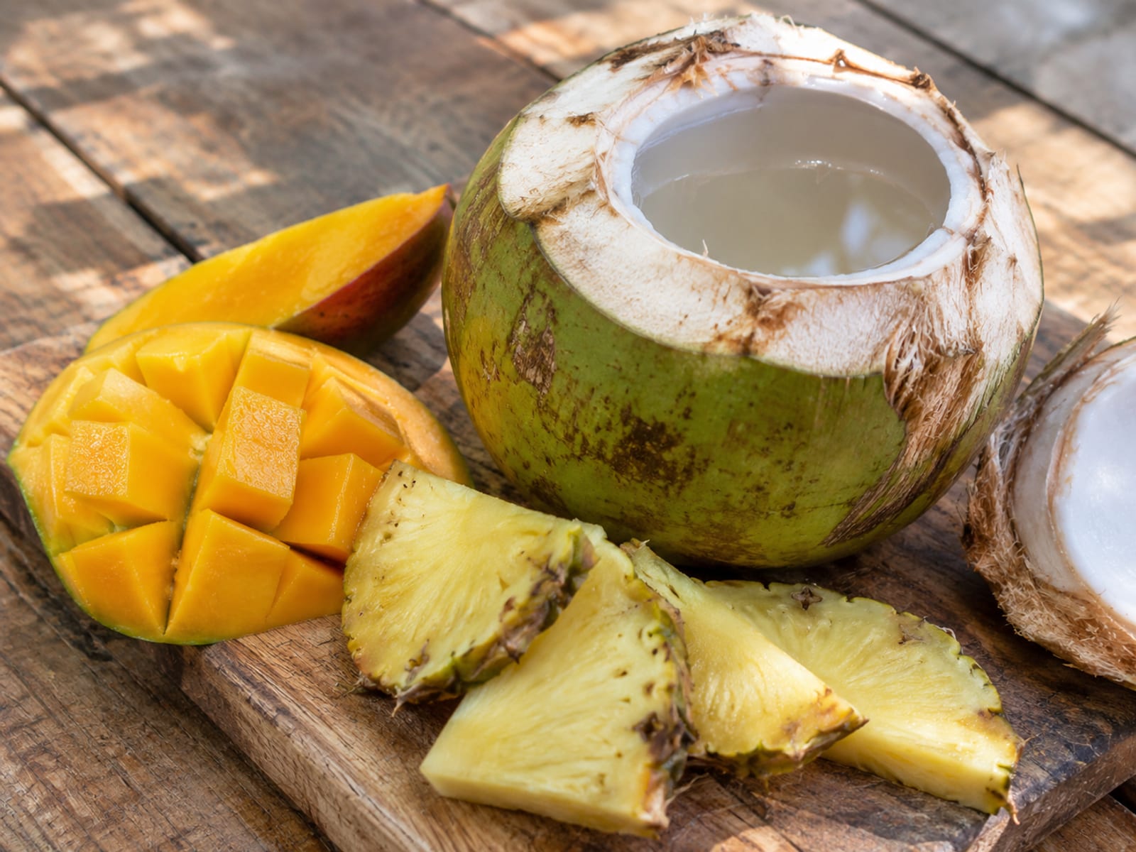 Fresh coconut water in a halved coconut beside slices of tropical fruit