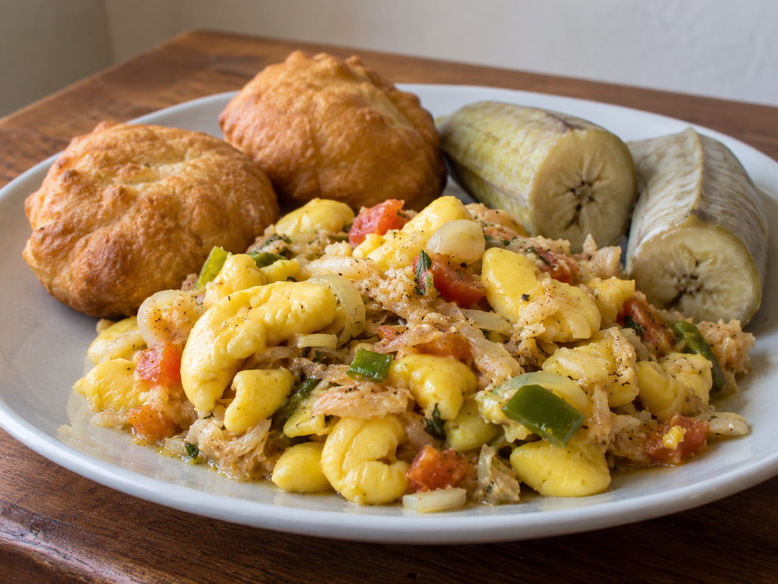 Ackee and saltfish with fried dumplings and boiled green bananas on a plate