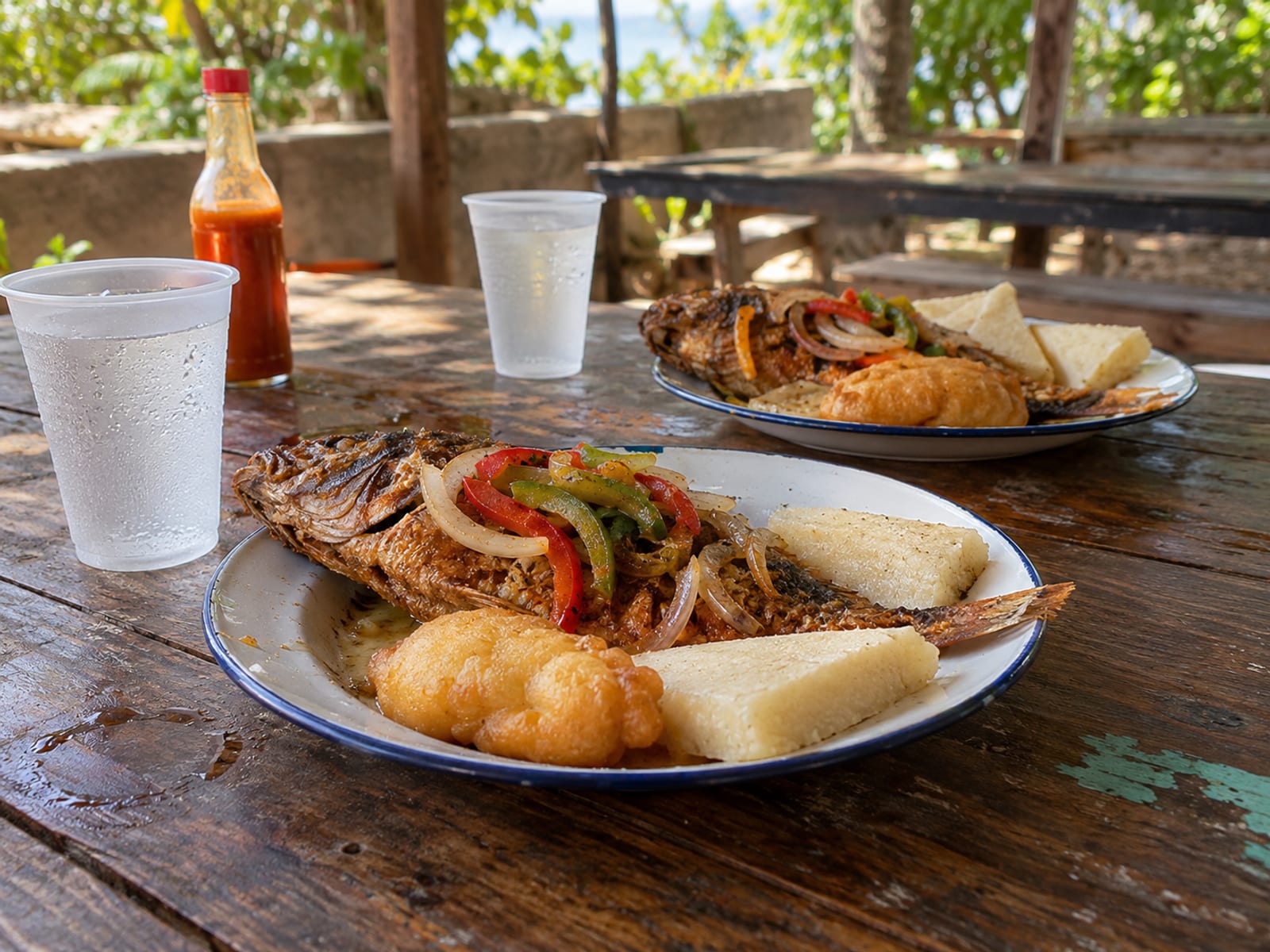 Plates of fried fish with bammy and festival on a plain cookshop table
