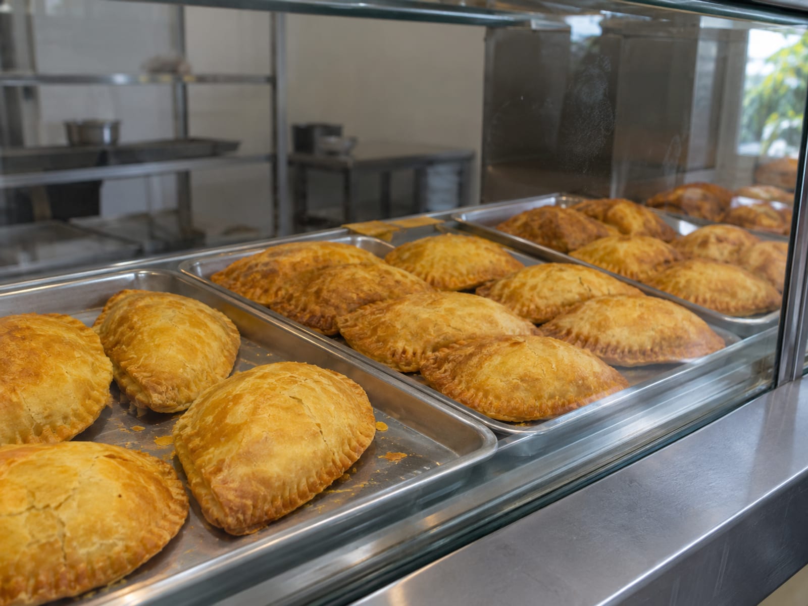 A plain glass bakery counter with trays of baked golden patties and no signs or labels