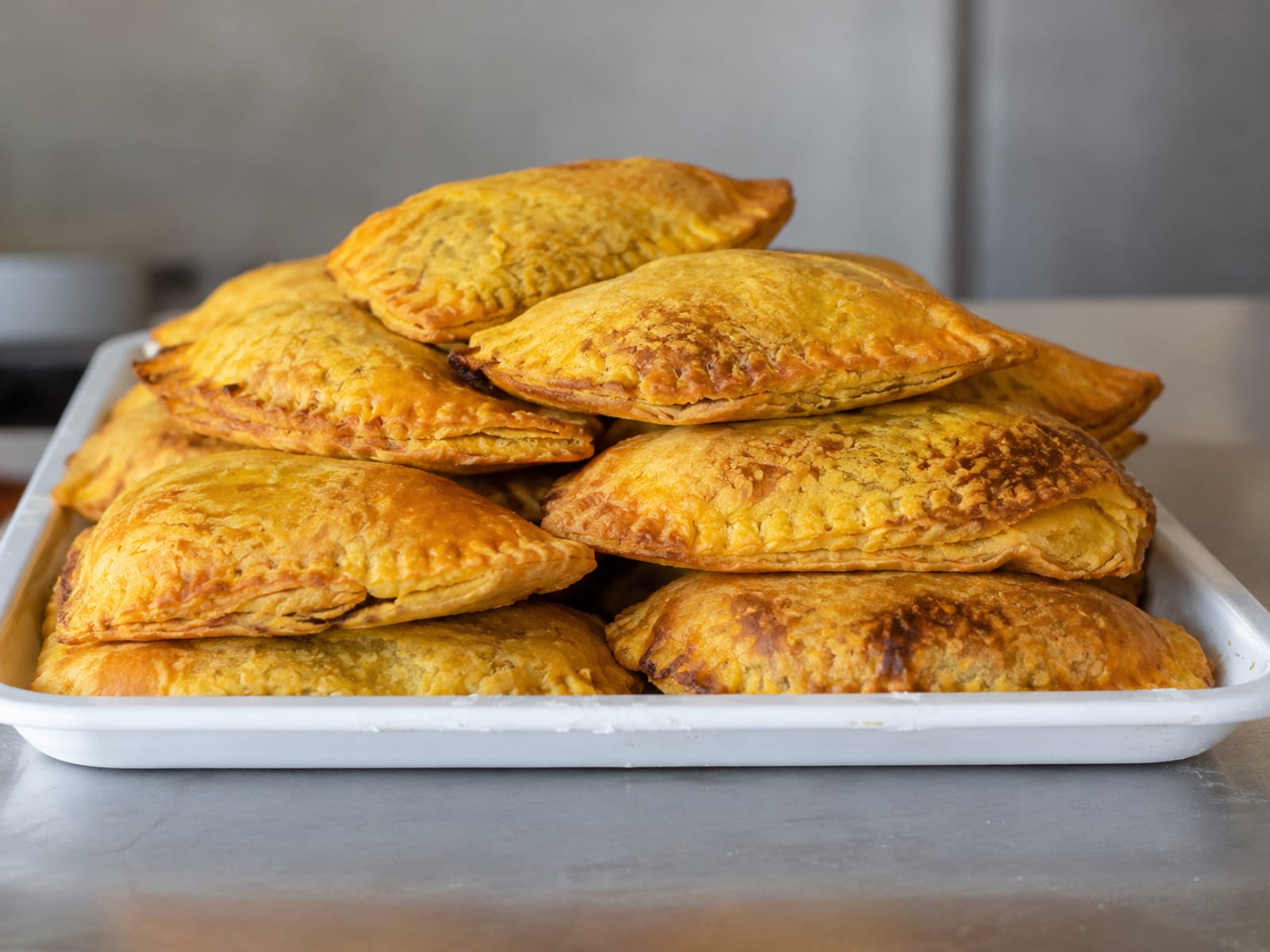 A plain white takeaway tray holding a stack of golden patties on a generic restaurant counter
