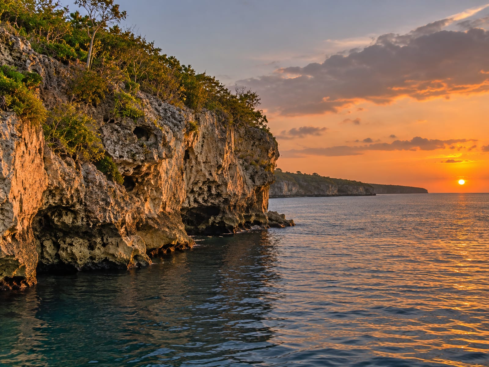 Rocky Negril cliffs at sunset above calm turquoise water
