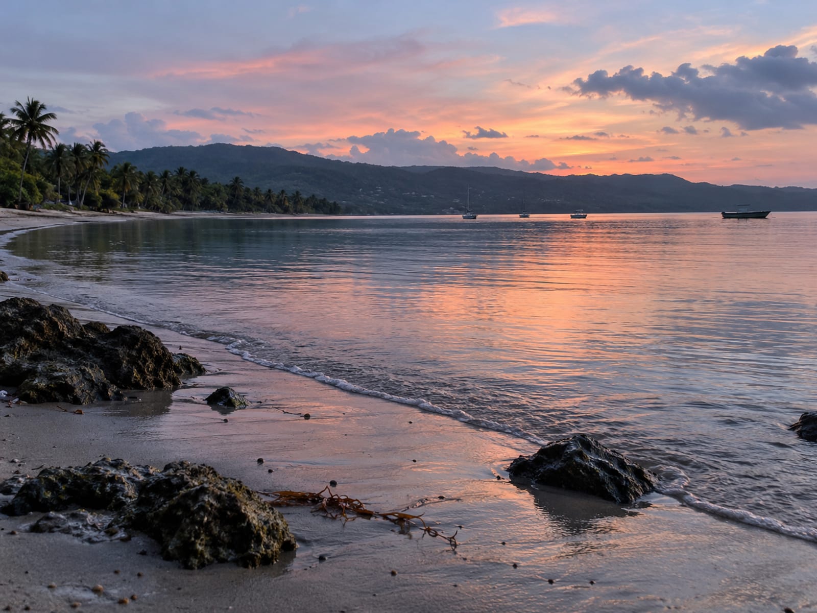 A calm bay at dusk with small boats and a curved shoreline