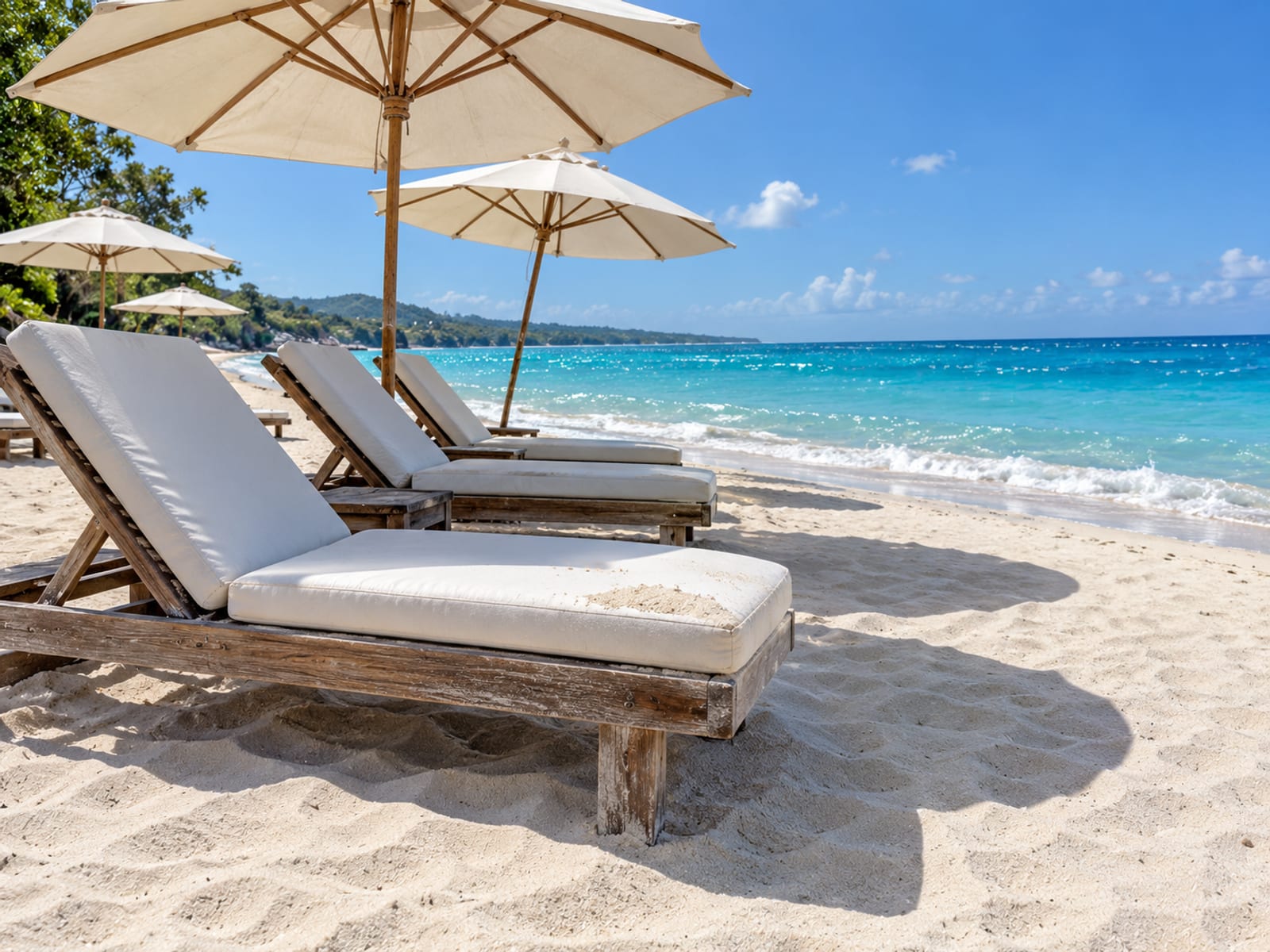 Empty sun loungers and umbrellas on a pale beach beside turquoise water