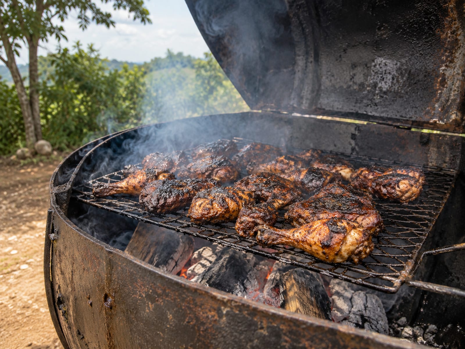 A steel jerk drum grill with smoking pimento wood and jerk meat on the rack