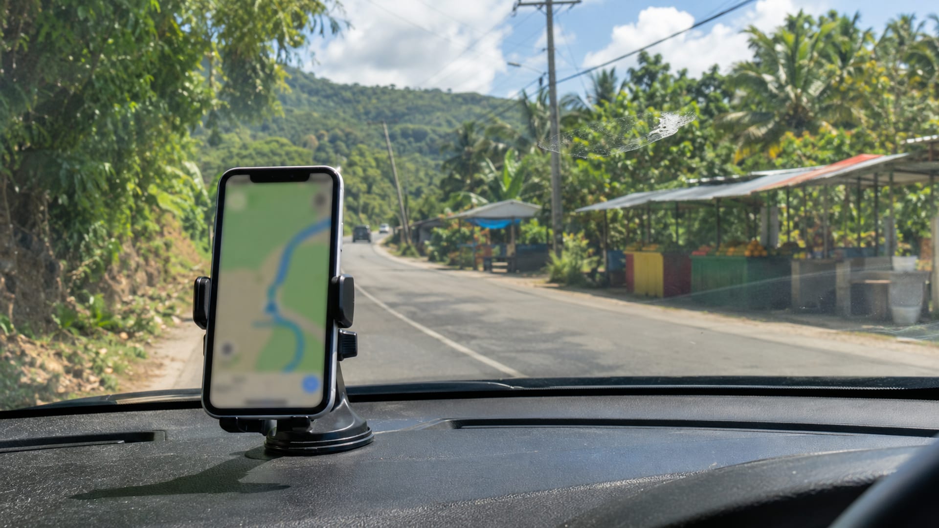 A phone with a blurred map on a dashboard, roadside food stalls ahead